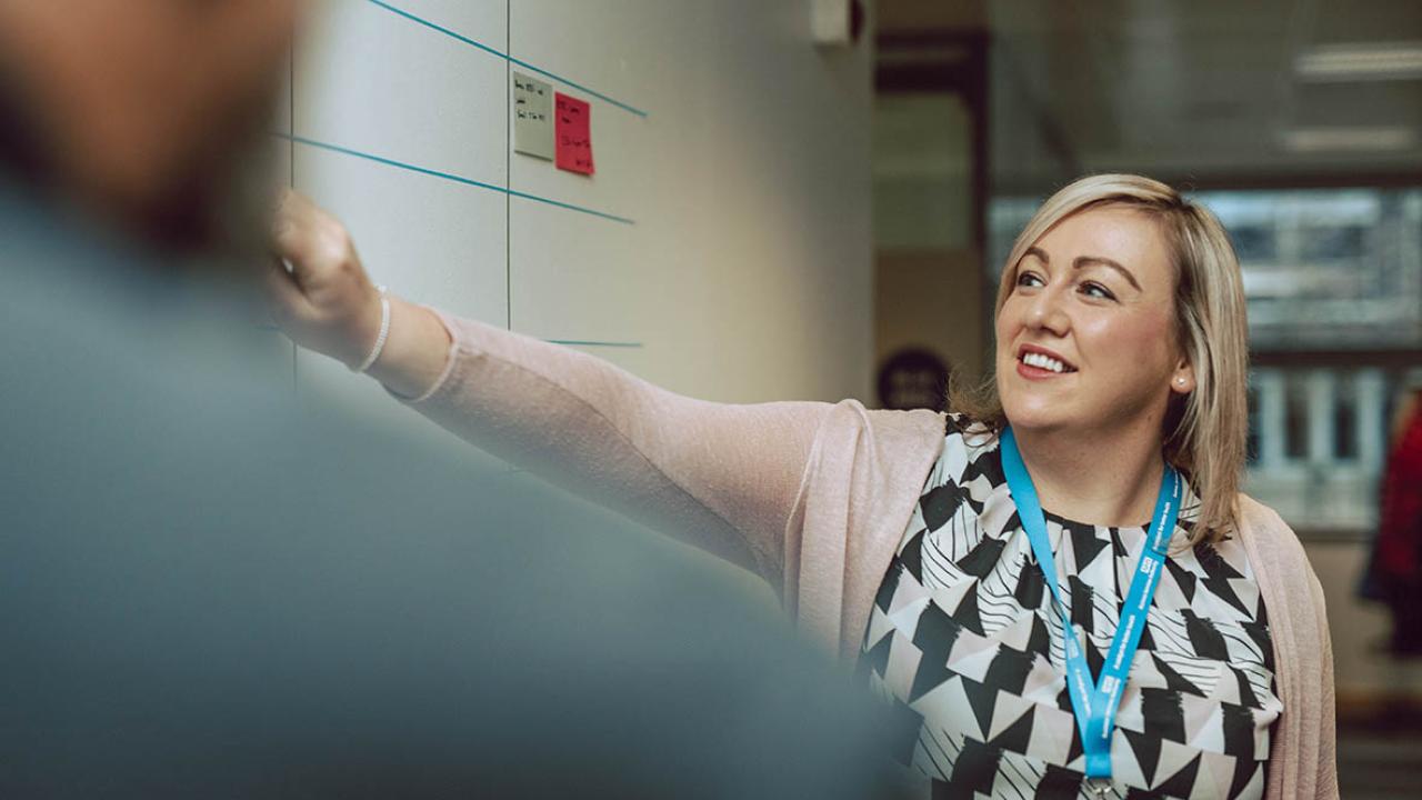 Woman points at board smiling